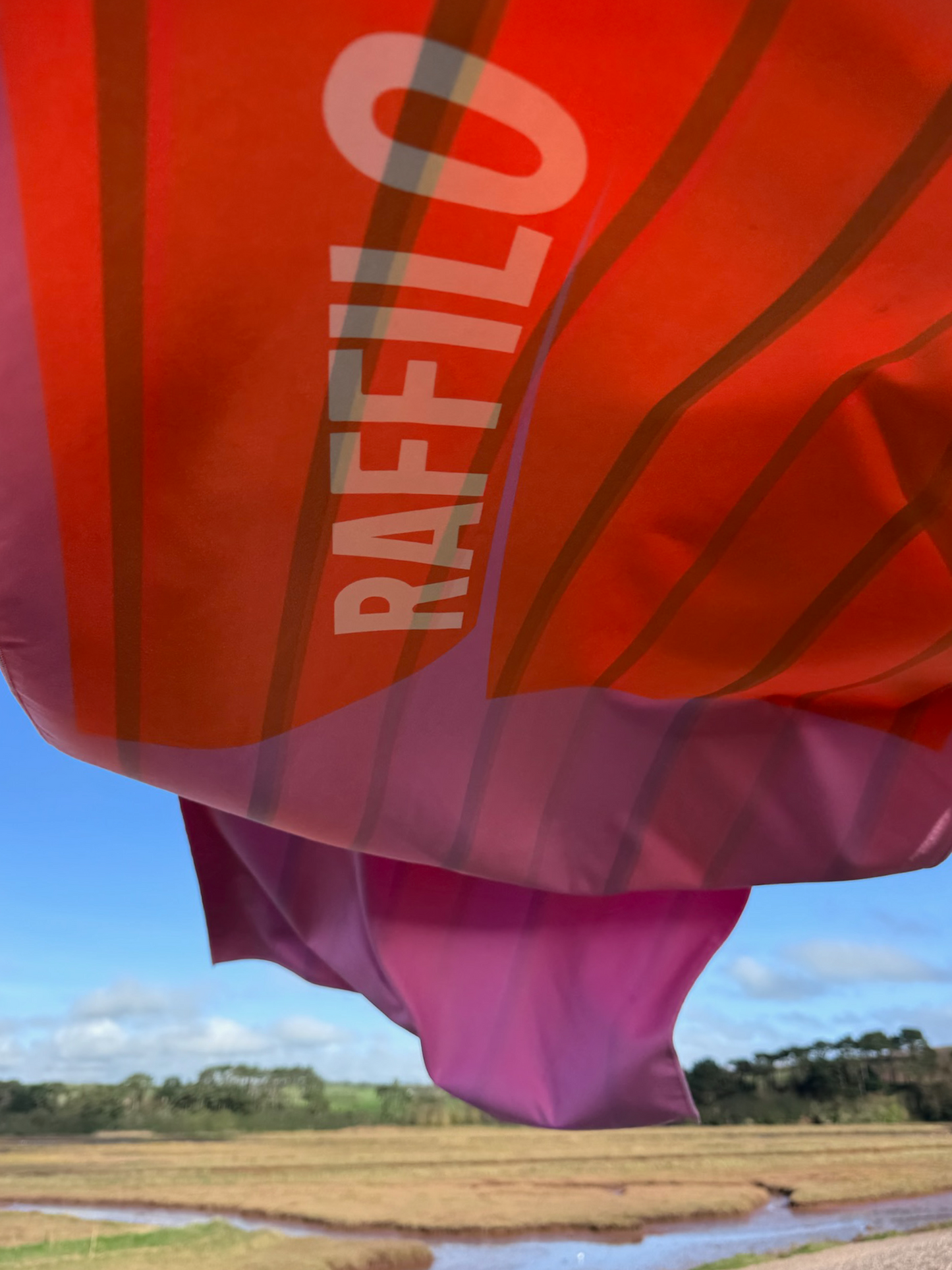 Raffilo Lightweight Dog Beach Towel in Flamingo Sunset, quick dry and perfect for travel, floating in the wind.